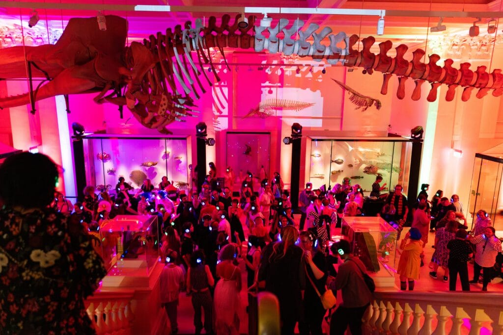 Silent disco crowd beneath dinosaur skeletons at Jurassic Lounge Australian Museum Sydney