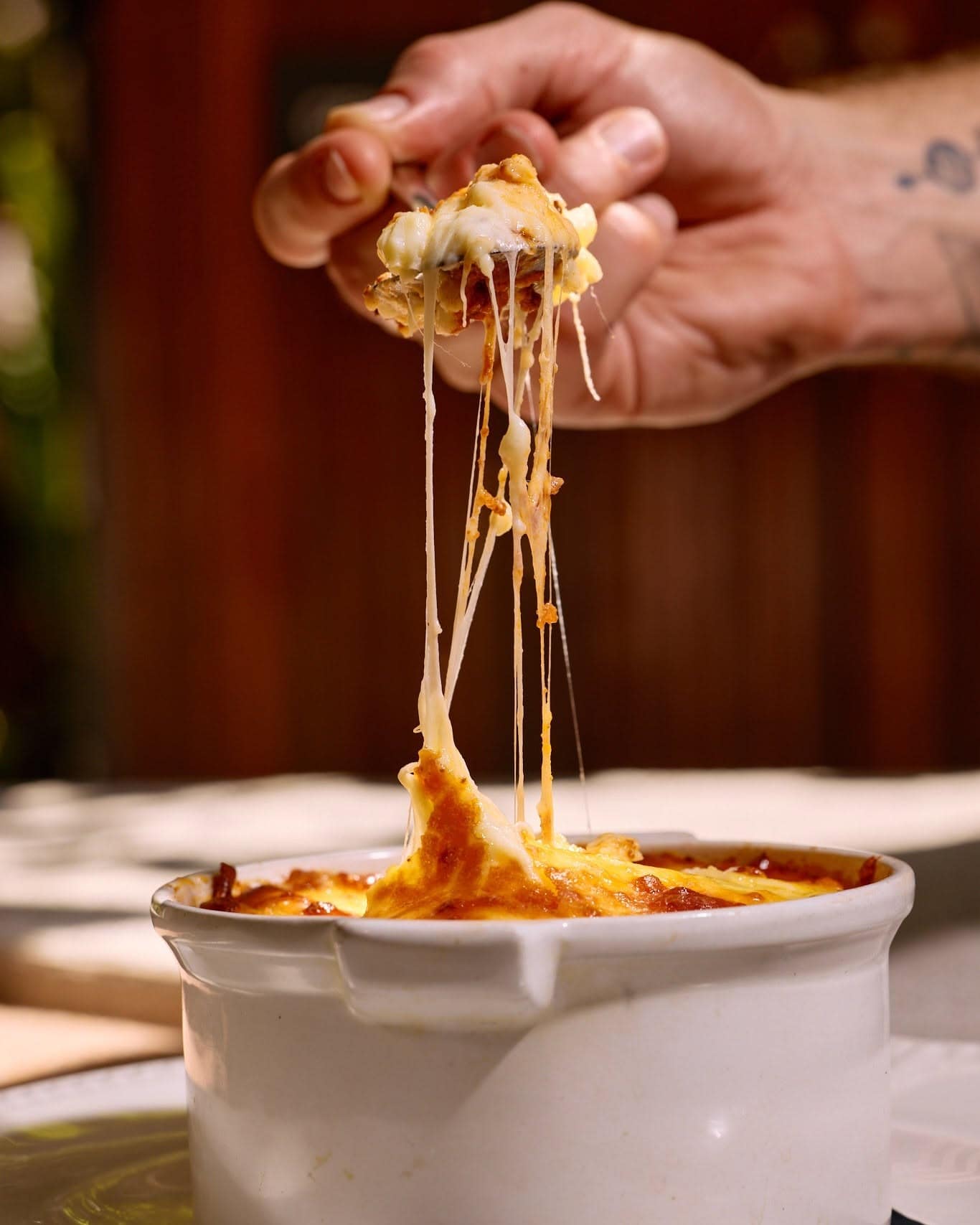 A fork pulls cheese from a white ramekin at Yamas Greek restaurant.