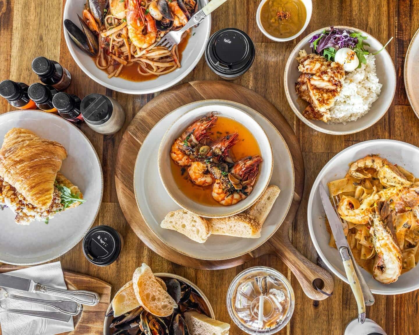 A brown table with several bowls of seafood dishes.