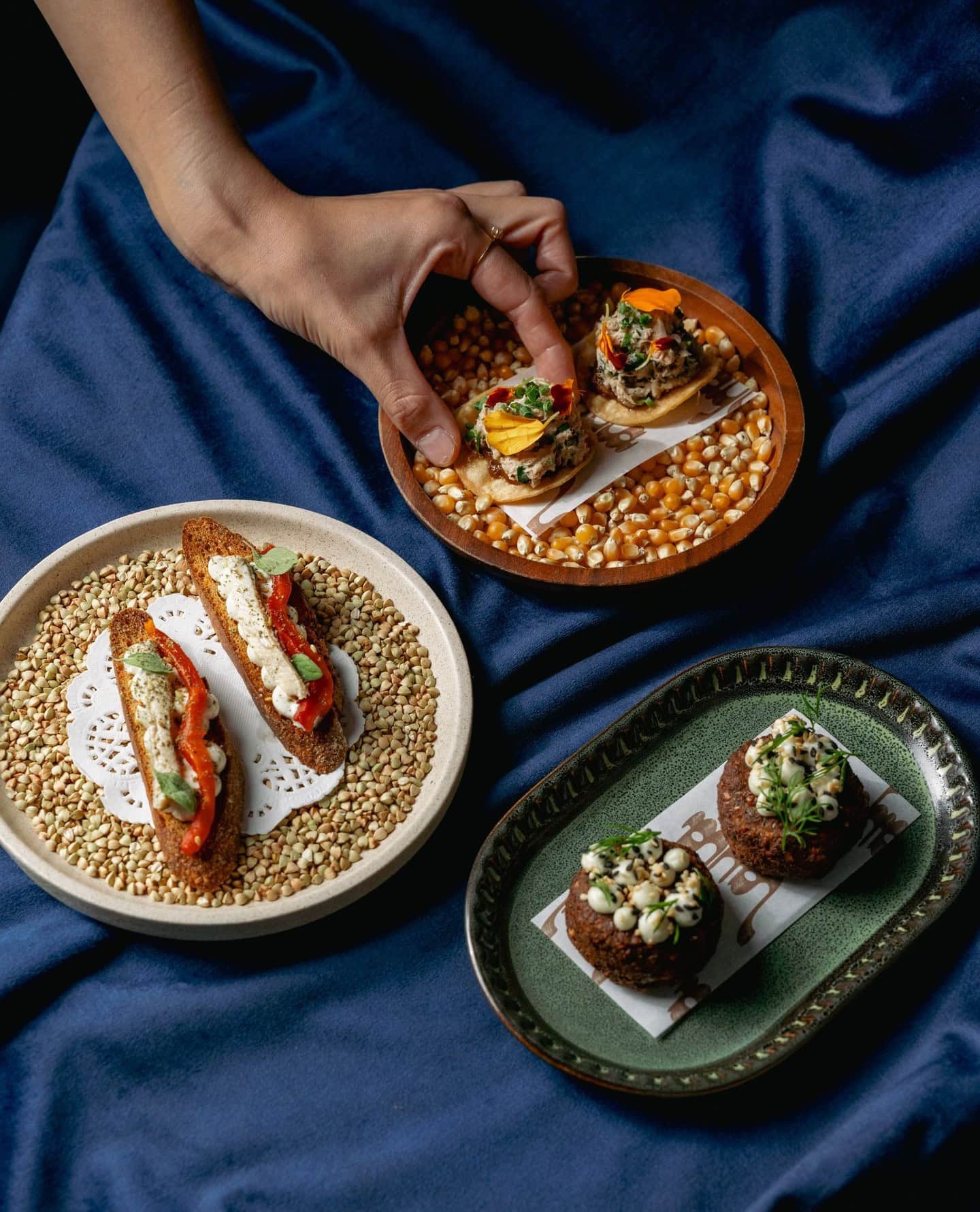 Three entree plates on a blue tablecloth at Layla West End.