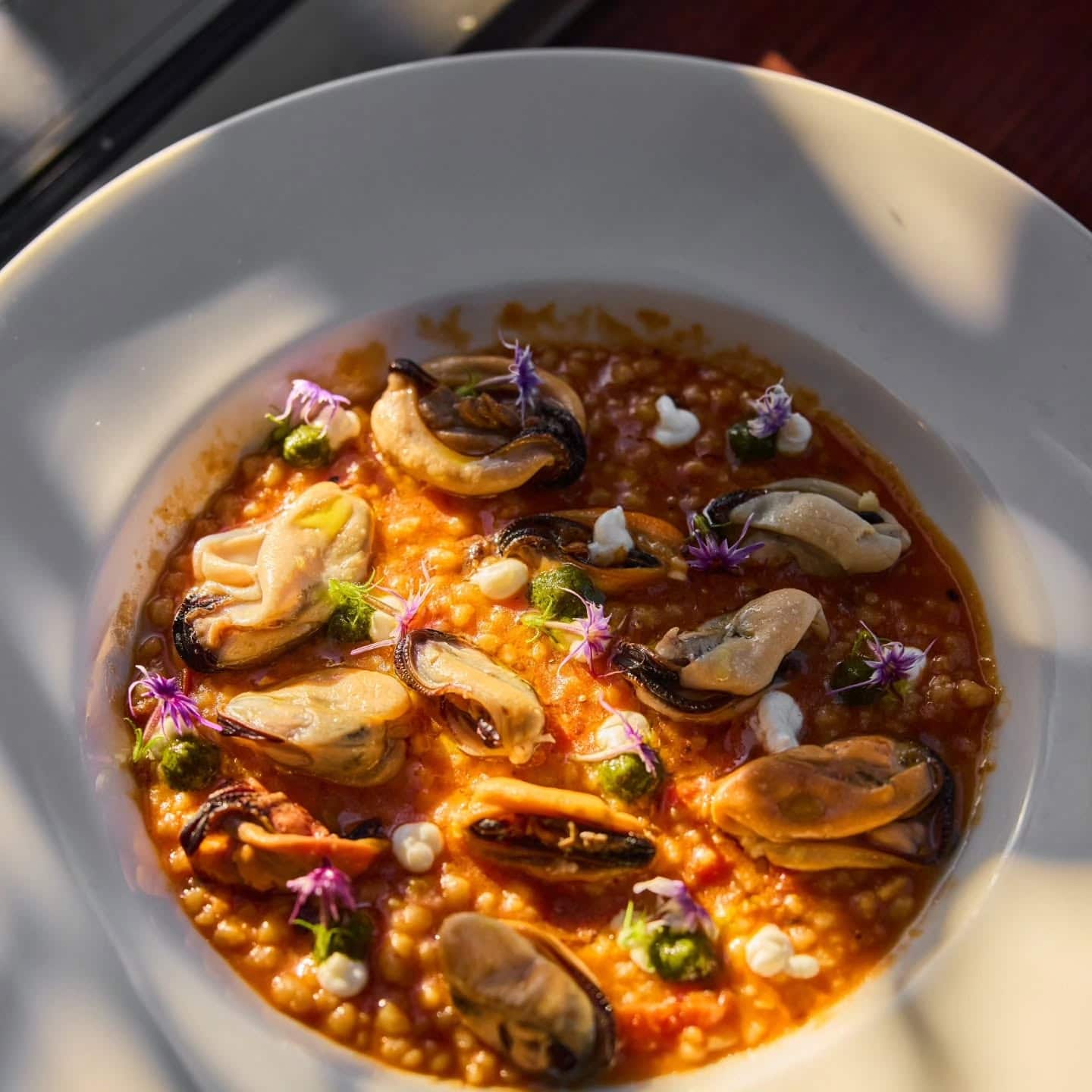 Fregole pasta with mussels and garnished with flowers.