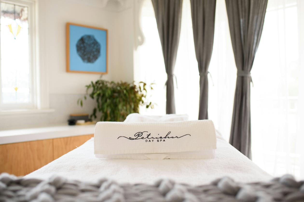 A close up shot of a branded towel rolled up on a massage table at Petrichor Day Spa.