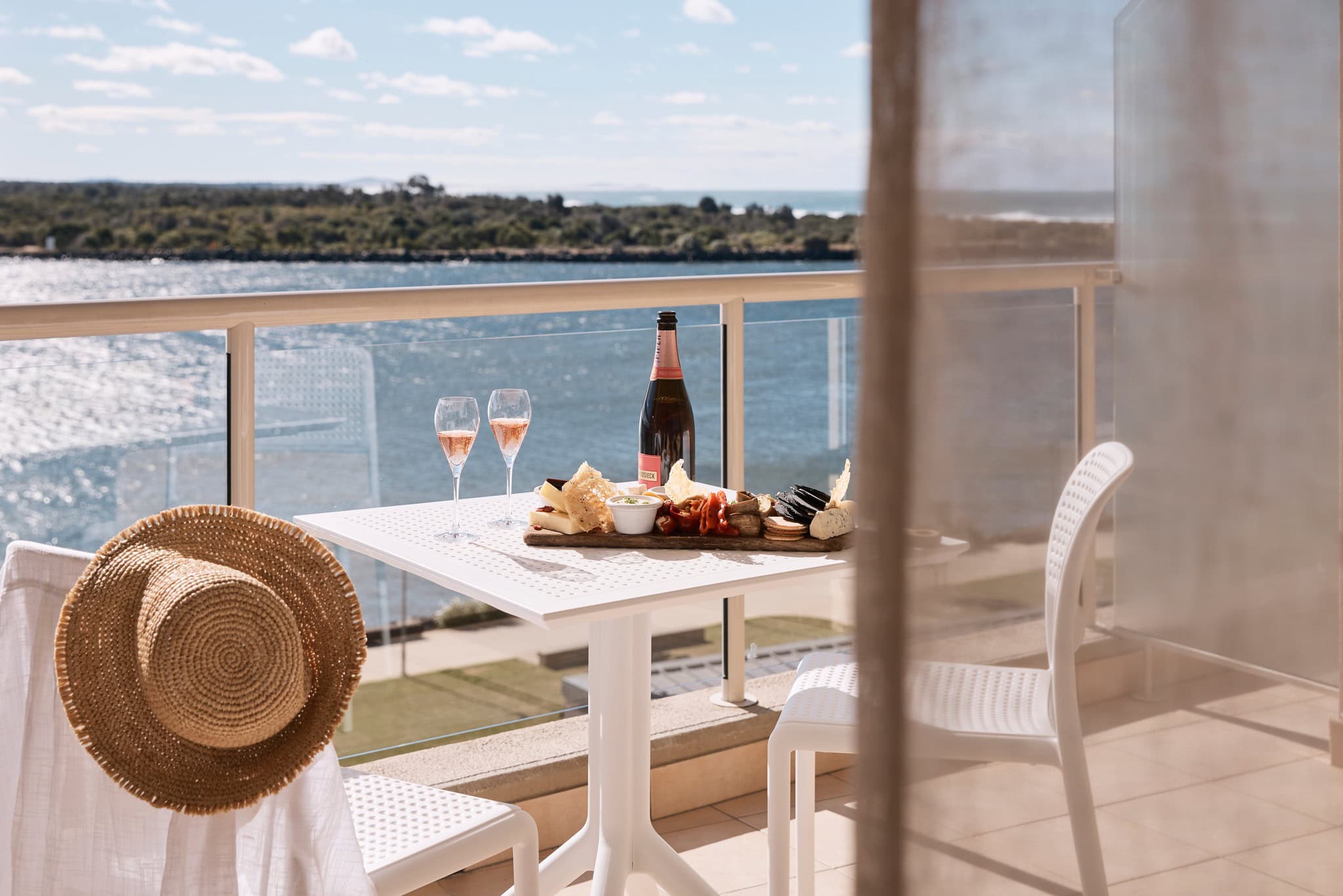 The balcony at Rydges Port Macquarie set with a champagne bottle and two glasses.