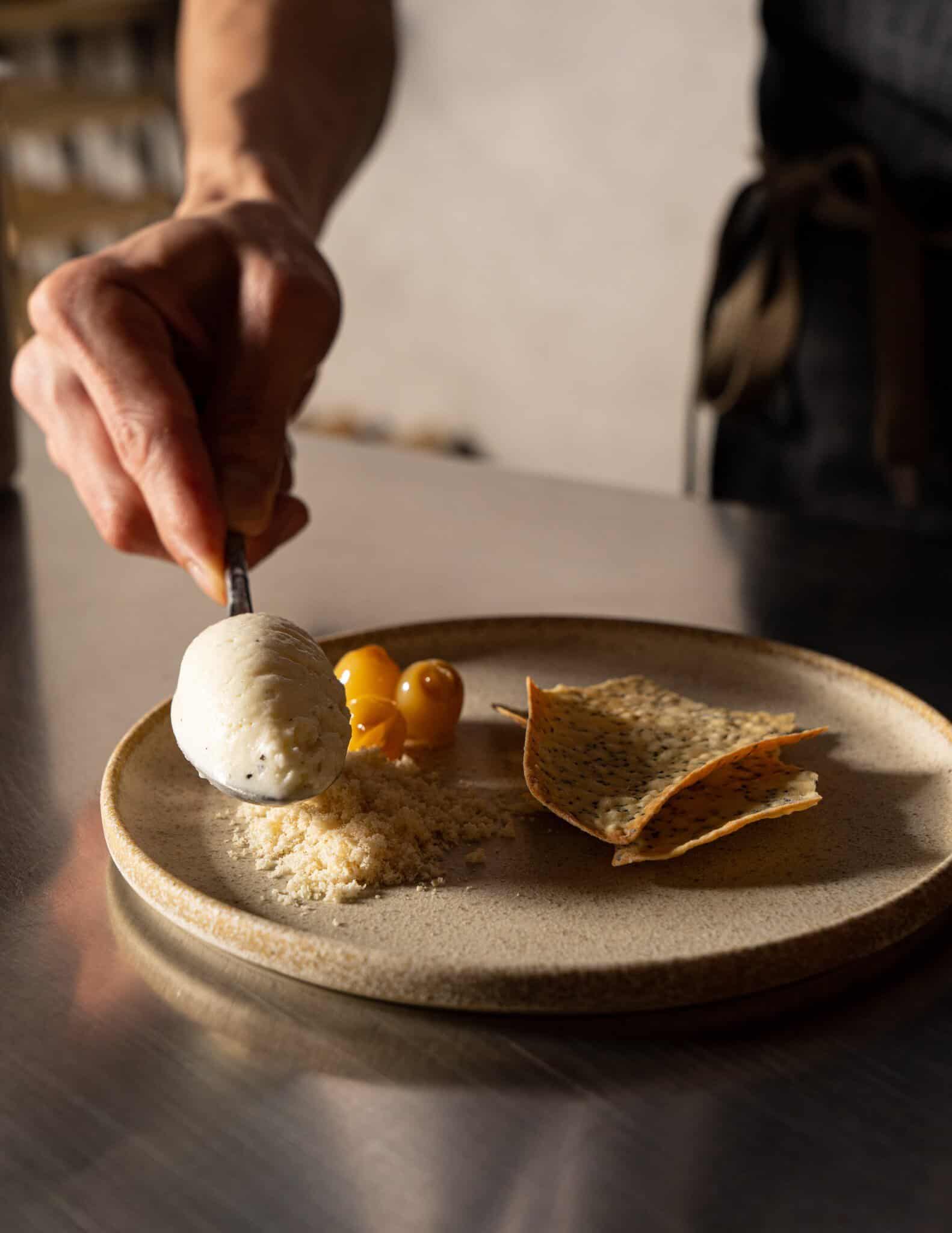 Chef plating the cheese course with a quenelle, crumble, glazed fruit and seeded crisps at Restaurant Ka, Darlinghurst Sydney