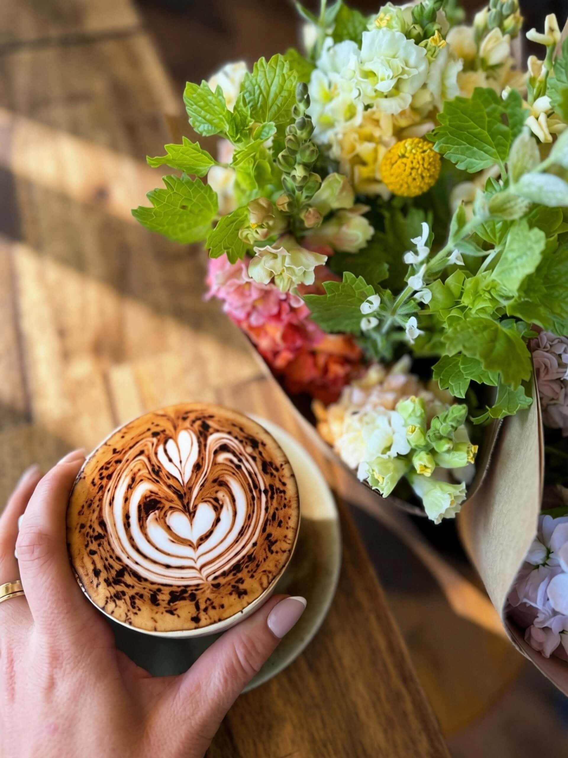 A coffee with fresh flowers in the background at Agostina in Port Macquarie.