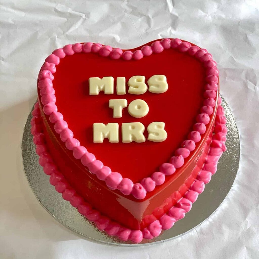 Glossy red heart-shaped chocolate smash cake with pink piped border and white chocolate "Miss to Mrs" lettering, by Sydney Smash Cakes, Rose Bay Sydney