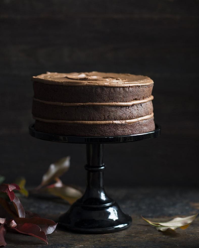 Three-layer chocolate cake with chocolate buttercream on a black cake stand, a special occasion cake by Flour and Stone bakery, Woolloomooloo Sydney