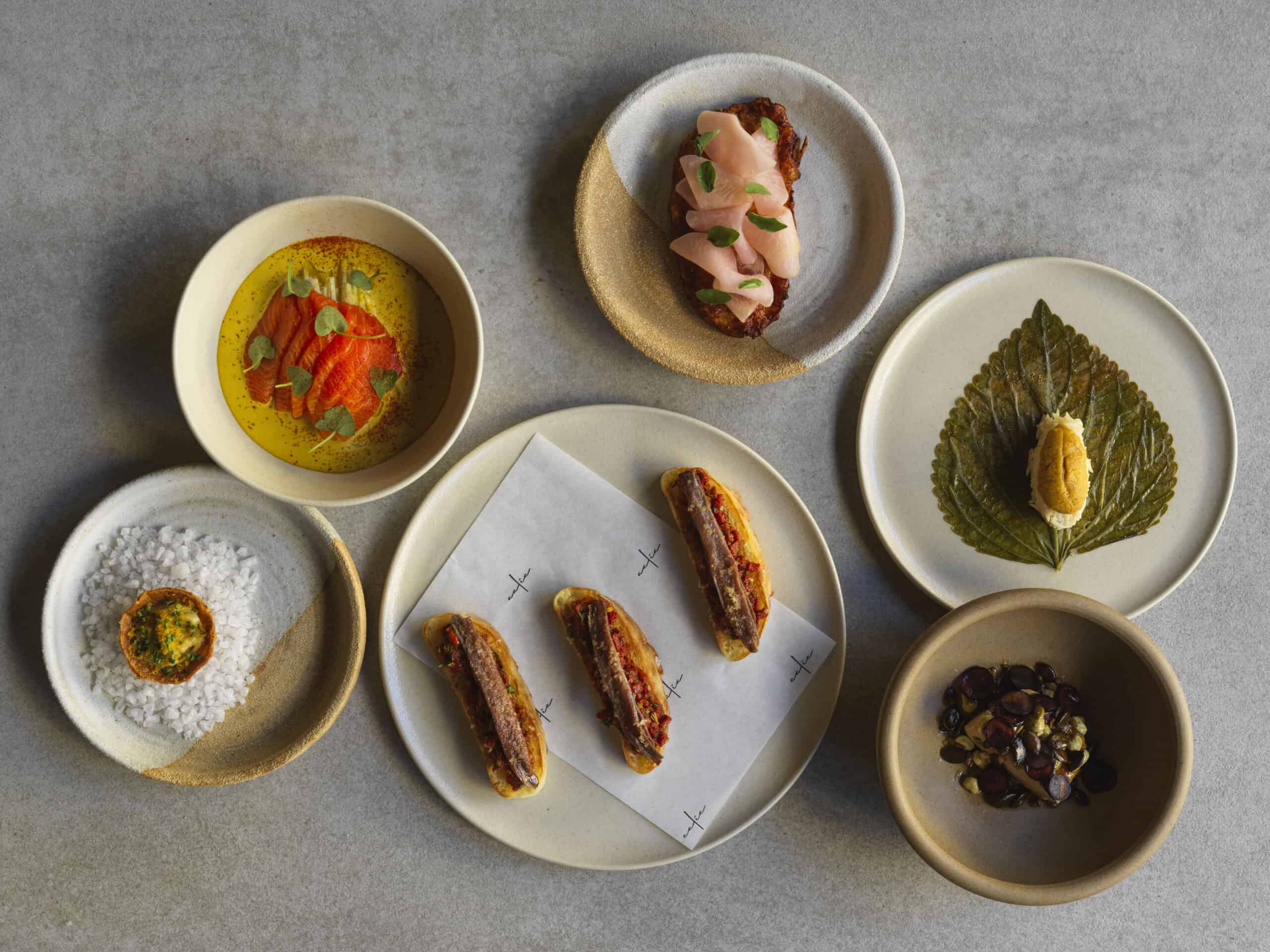 Spread of raw dishes and mezze including sea urchin, cured fish and anchovy toasts at Aalia, Martin Place Sydney CBD, awarded two Hats in the Good Food Guide 2026
