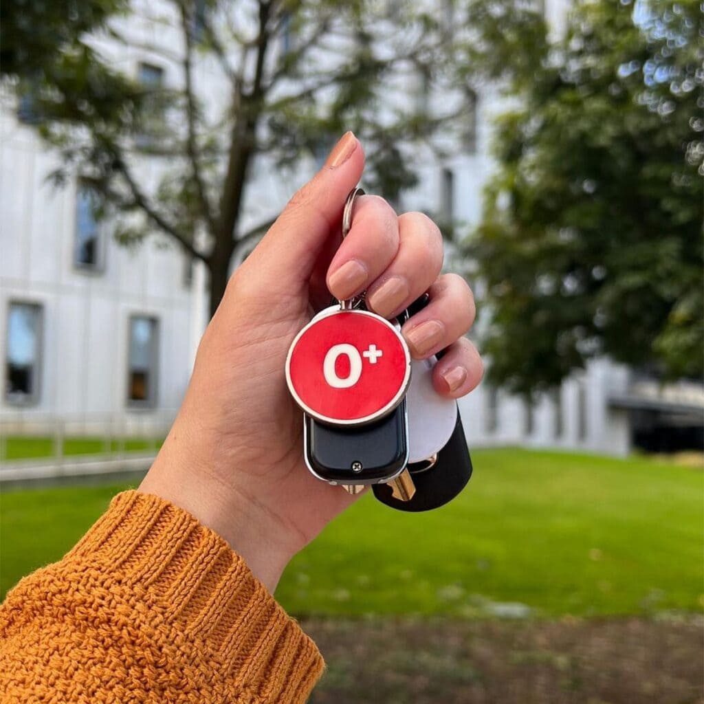 Someone holding up an O+ Lifeblood keyring. 