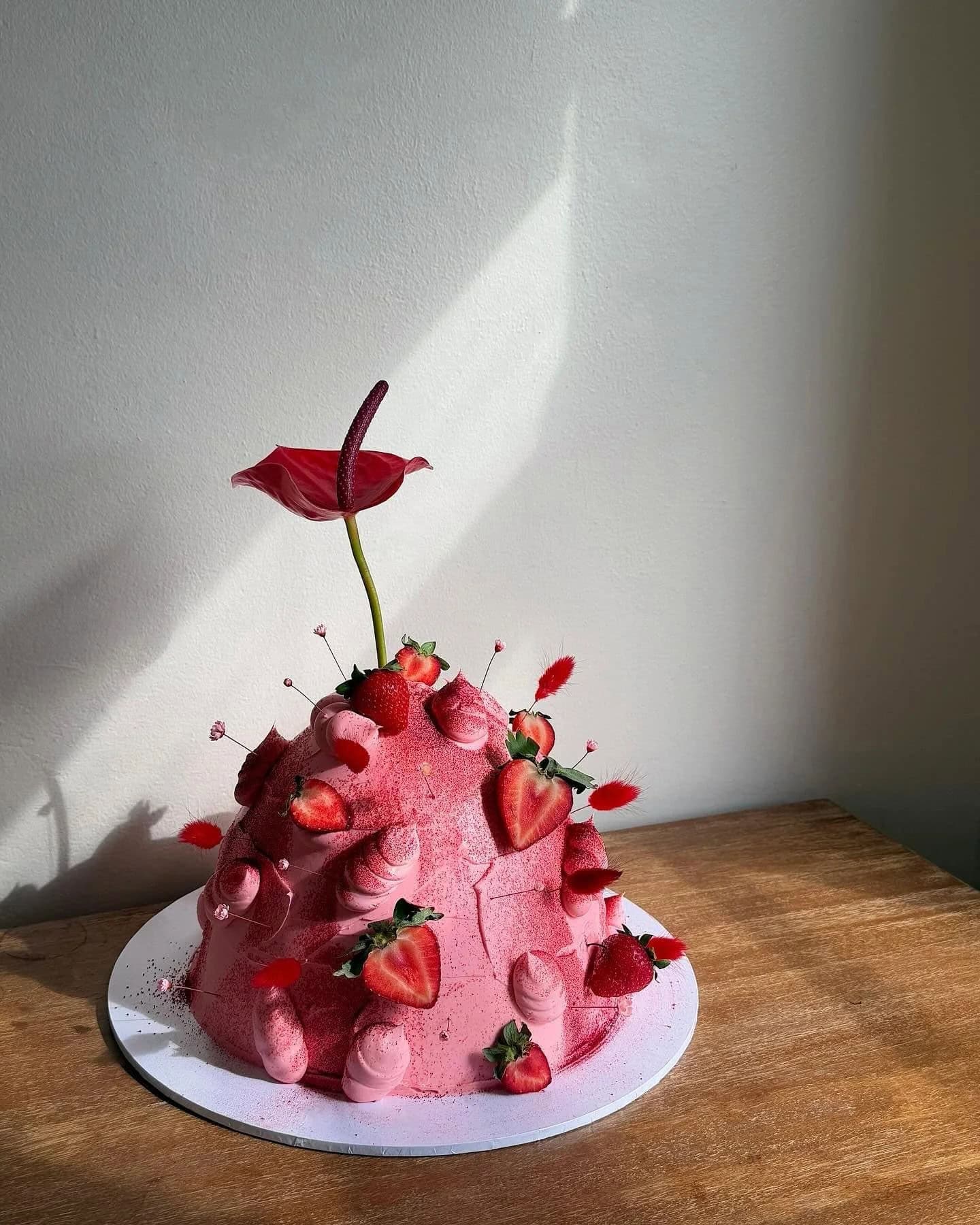 Sculptural pink buttercream dome cake decorated with fresh strawberries, dried flowers and a red anthurium, by Javi Bakes, Rushcutters Bay Sydney