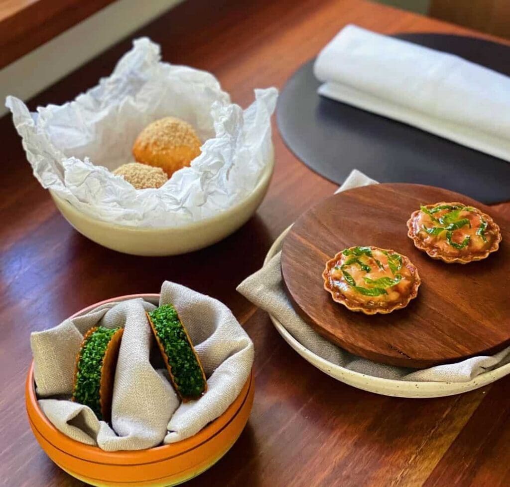 Snacks including tartlets, chive-topped crisps and sesame-crusted bites at Sixpenny, Stanmore Sydney, awarded three Hats in the Good Food Guide 2026