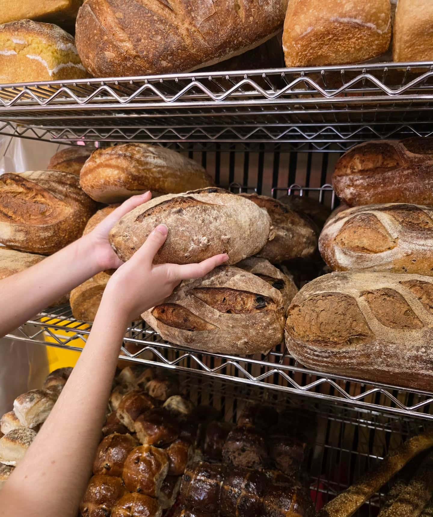 An employee picking a sourdough loaf off the rack at Danny's Bread in Brisbane.