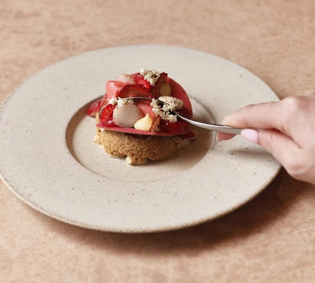 Strawberry dessert topped with elderflowers on a biscuit base at Aria, Sydney CBD near the Opera House, awarded two Hats in the Good Food Guide 2026