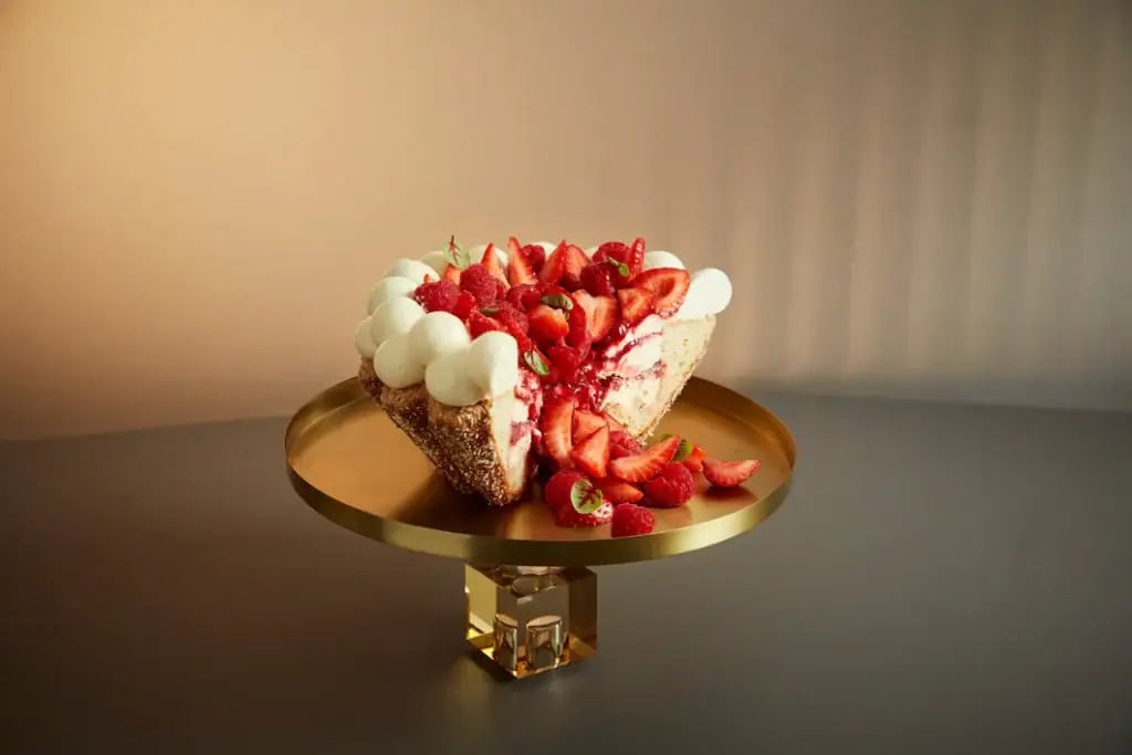 Sliced Sweet Charlotte cake with whipped cream, fresh strawberries and raspberries on a gold cake stand, from The Art of Cake collection at Four Seasons Hotel Sydney, Sydney CBD