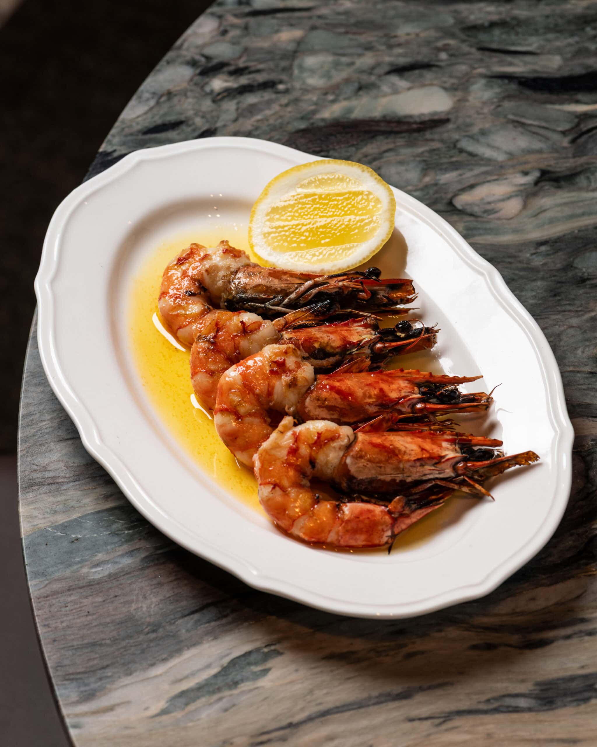 A plate of large tiger prawns with a sliced lemon at High Road in Brisbane