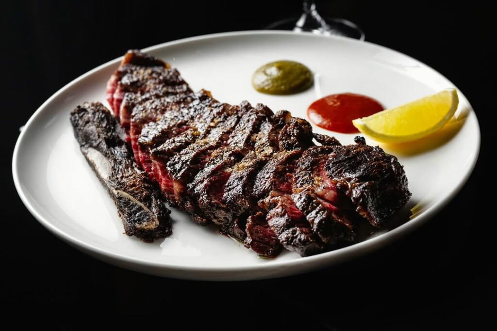 Sliced wood-fired steak with chimichurri, red sauce and lemon at 20 Chapel, Marrickville Sydney, awarded one Hat in the Good Food Guide 2026